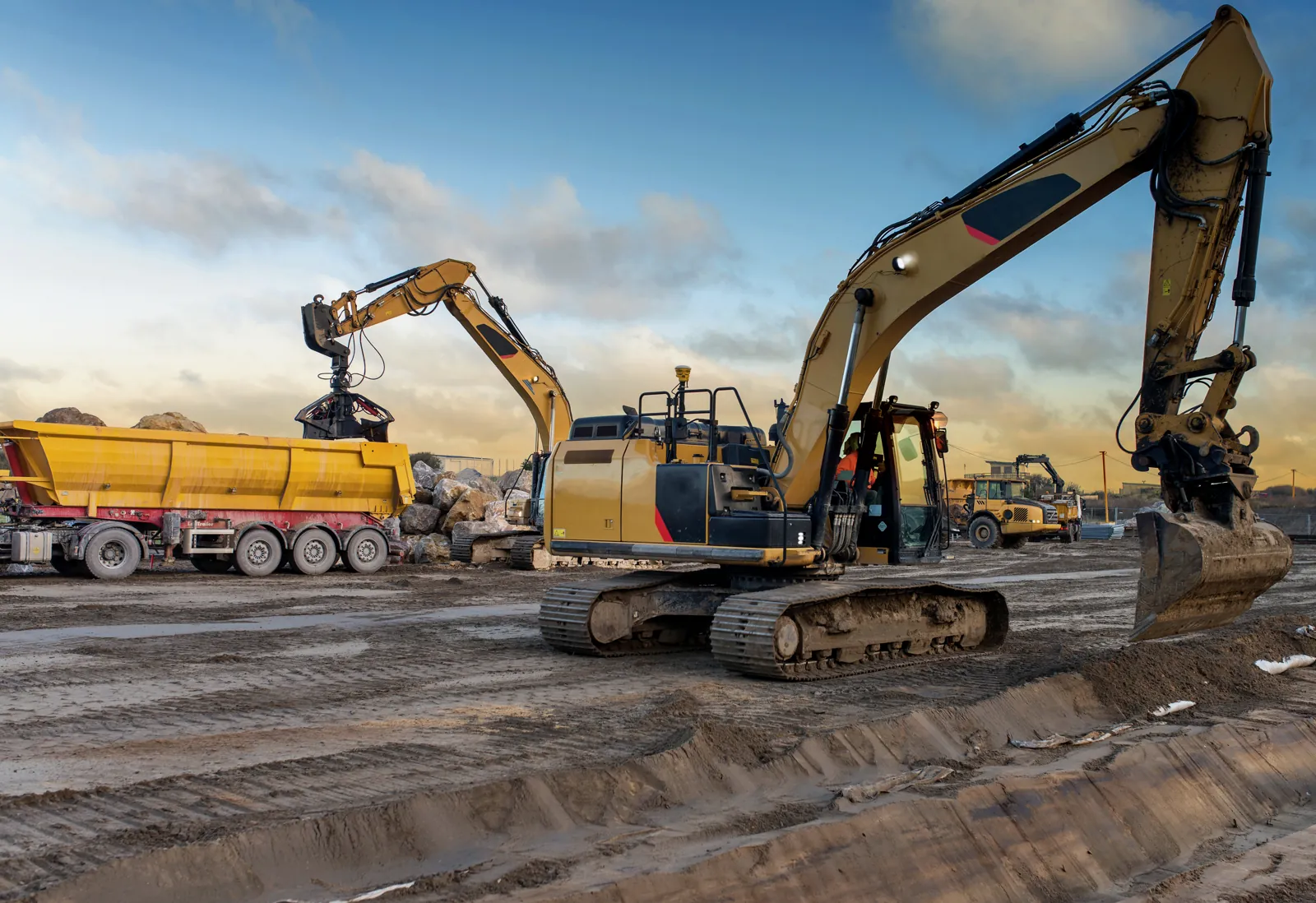 Excavators and trucks at work on a construction site at dawn